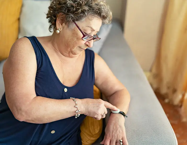 Elderly woman pressing the button of her Wearable Personal Emergency Response System.