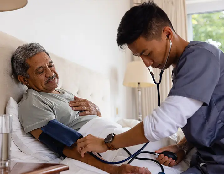 A male nurse checking the vitals of an elderly man after he pressed the emergency call button on his PERS unit.